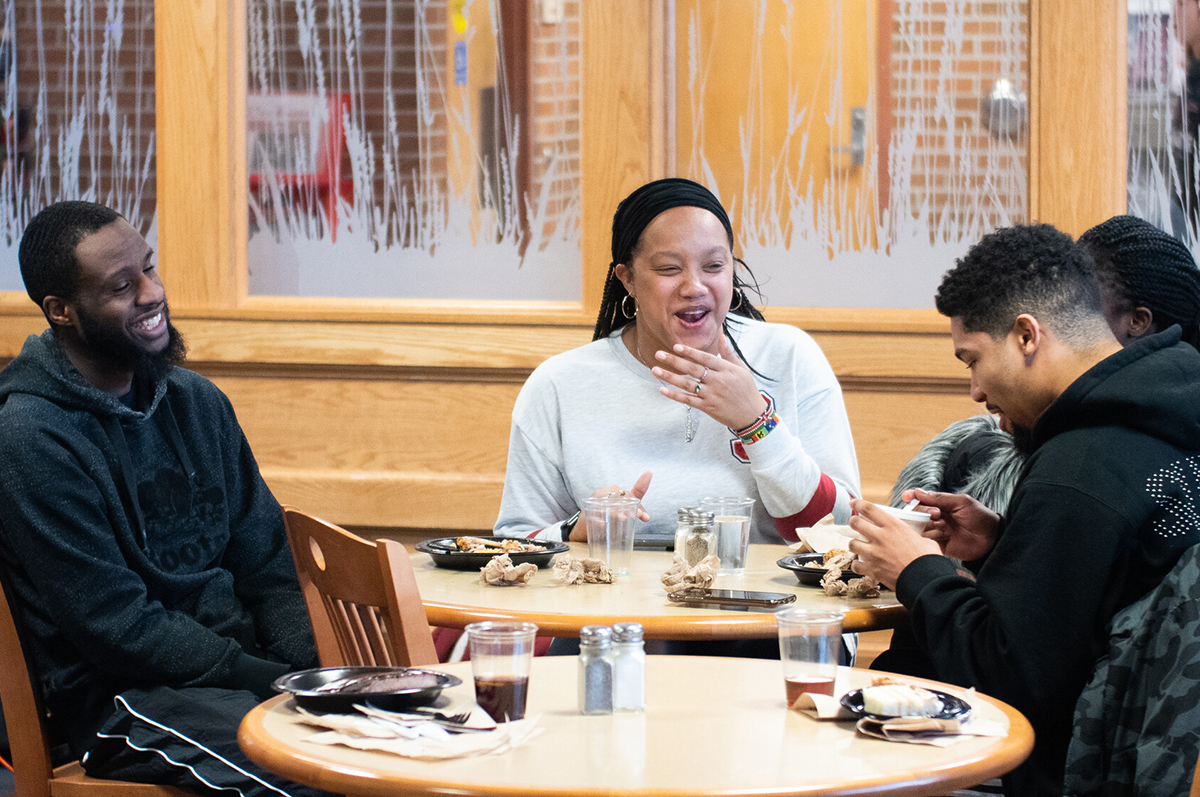 Three people sitting at table with plates of food